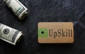 Paper tag with UpSkill text and hundred dollar bills