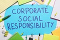 Paper text balloon with phrase Corporate Social Responsibility among office supplies on white table, flat lay Royalty Free Stock Photo