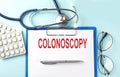 Paper with text COLONOSCOPY on a blue background with stethoscope and pills