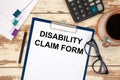 Paper with text - DISABILITY CLAIM FORM on the table, calculator and cup of coffee