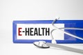 Paper with text E-HEALTH on blue background with stethoscope and pills