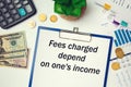 Paper with text - Fees charged depend on one`s income - on the table, calculator and money