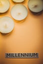 Paper with text millennium and white candles on orange table Royalty Free Stock Photo