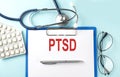 Paper with text PTSD on a blue background with stethoscope and pills