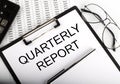 Paper with text QUARTERLY REPORT on the table on the chart Royalty Free Stock Photo