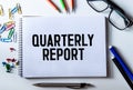 Paper with text QUARTERLY REPORT on the table on chart Royalty Free Stock Photo