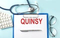 Paper with text QUINSY on a blue background with stethoscope and pills