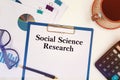Paper with text - Social Science Research on the table, calculator and cup of coffee Royalty Free Stock Photo