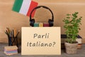 paper with text & x22;parli italiano?& x22;, flag of the Italia, books, headphones, pencils Royalty Free Stock Photo