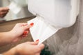 Paper towel dispenser. Hand of woman takes paper towel in bathroom. Royalty Free Stock Photo