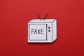 Paper TV with word Fake on red background, top view. Information warfare concept Royalty Free Stock Photo