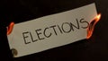 Elections word written on white paper burns. Fire with smoke and ashes on black background Royalty Free Stock Photo