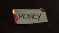 Money word written on white paper burns. Fire with smoke and ashes on black background Royalty Free Stock Photo