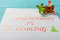 Paper written with Christmas is coming and cute santa claus on sled & reindeer on background Royalty Free Stock Photo