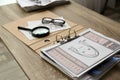 Papers with suspect`s portrait, palm print and magnifying glass on wooden table in detective office