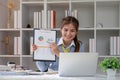 Paperwork. Happy smiling asian business woman in formal wear sitting at wooden desk in modern office and reading report Royalty Free Stock Photo