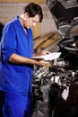 Paperwork, man and mechanic reading at engine of car, repair and maintenance. Checklist, technician and serious person