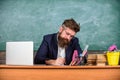 Paperwork part of teachers life. Teacher bearded hipster with eyeglasses sit in classroom chalkboard background. School