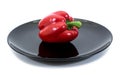 Red bell pepper in a plate over white background. Sweet pepper in black plate isolated Royalty Free Stock Photo