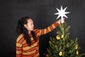 Papuan girl putting white star on top of Christmas tree