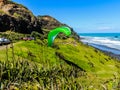 Para glider soars over the beach waves and hills at Murawai Beach Auckland New Zealand Royalty Free Stock Photo