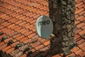 Parabolic antenna stuck on a stone chimney over roof