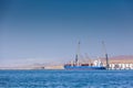 Paracas, Peru - 2019-12-05. A large cargo ship stands in port on loading off the coast of the ocean, in the back photo