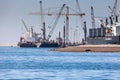 Paracas, Peru - 2019-12-05. In the port, cargo cranes are loading onto a cargo ship. Birds can be seen on the berug