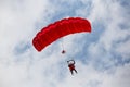 Parachuter descending with a red parachute Royalty Free Stock Photo