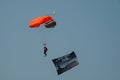 Parachuting US soldier with a banner against a clear blue sky