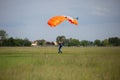 Parachutist with Orange Parachute near to the Ground Preparing for Landing Royalty Free Stock Photo