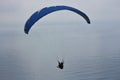 Parachutist gliding over calm sea