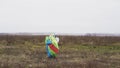 Parachutist walking with a bright chute in his hands after landing on a field. Action. Male jumper in a white windproof Royalty Free Stock Photo