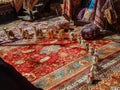 A parade of tiny camels in a semi-circle on a Persian rug iwth hangings and taspestry stools behind