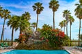 Paradise at the beach - Tall palm trees frame  waterfall and beautiful vining flowers at the end of a swimming pool with the ocean Royalty Free Stock Photo