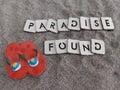 Paradise found message written on sand with a pair of red flip flops