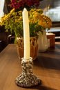 Paraffin candle in handmade candlestick made of cones and white beads. Home interior vertical photo
