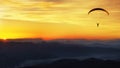 Paraglide silhouette over mountains at sunset