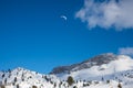 Paraglider above Rofan mountains, winter landscape with blue sky and clouds