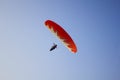 Paraglider in a black gondola on a red parachute flies in a clear blue sky bottom view Royalty Free Stock Photo