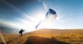 paraglider with a blue parachute takes off. A man takes off and lands on a yellow field. a man preparing to take off Royalty Free Stock Photo