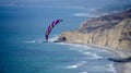 Paraglider over the ocean with cliffs and beach below