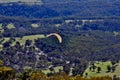 A paraglider flies over farmland