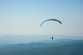A paraglider flies over a mountain valley on a sunny summer day. Royalty Free Stock Photo