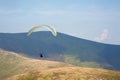 Paraglider flies over a mountain valley on a sunny summer day. Royalty Free Stock Photo