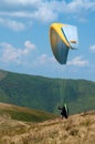 Paraglider flies over a mountain valley on a sunny summer day. Paragliding in the Carpathians in the summer. Royalty Free Stock Photo