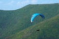 Paraglider flies over a mountain valley on a sunny summer day. Paragliding in the Carpathians in the summer. Royalty Free Stock Photo