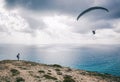 The paraglider flies over the sea, the girl watches him from the Royalty Free Stock Photo