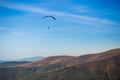 Paraglider flying over mountains peak in autumn day with beautiful aerial world view.