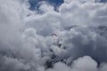 Paraglider flying in sky with fluffy clouds over mountains Royalty Free Stock Photo